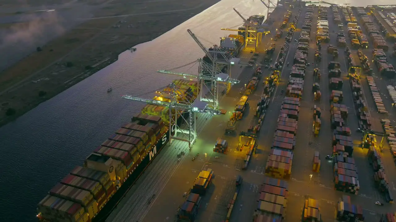 The Port of Oakland at night with containers being loaded on shipping vessels aerial orbiting view