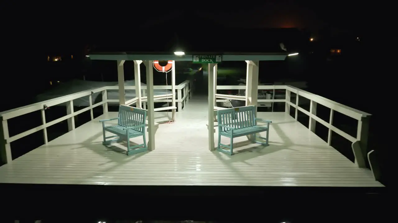 Reversing drone shot of a gazebo on the end of a private dock on a Florida lake with security camera signs and flotation device