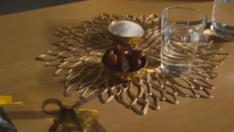 Bowl Of Dates With Glass Of Water On Table In Muslim Home Celebrating Eid