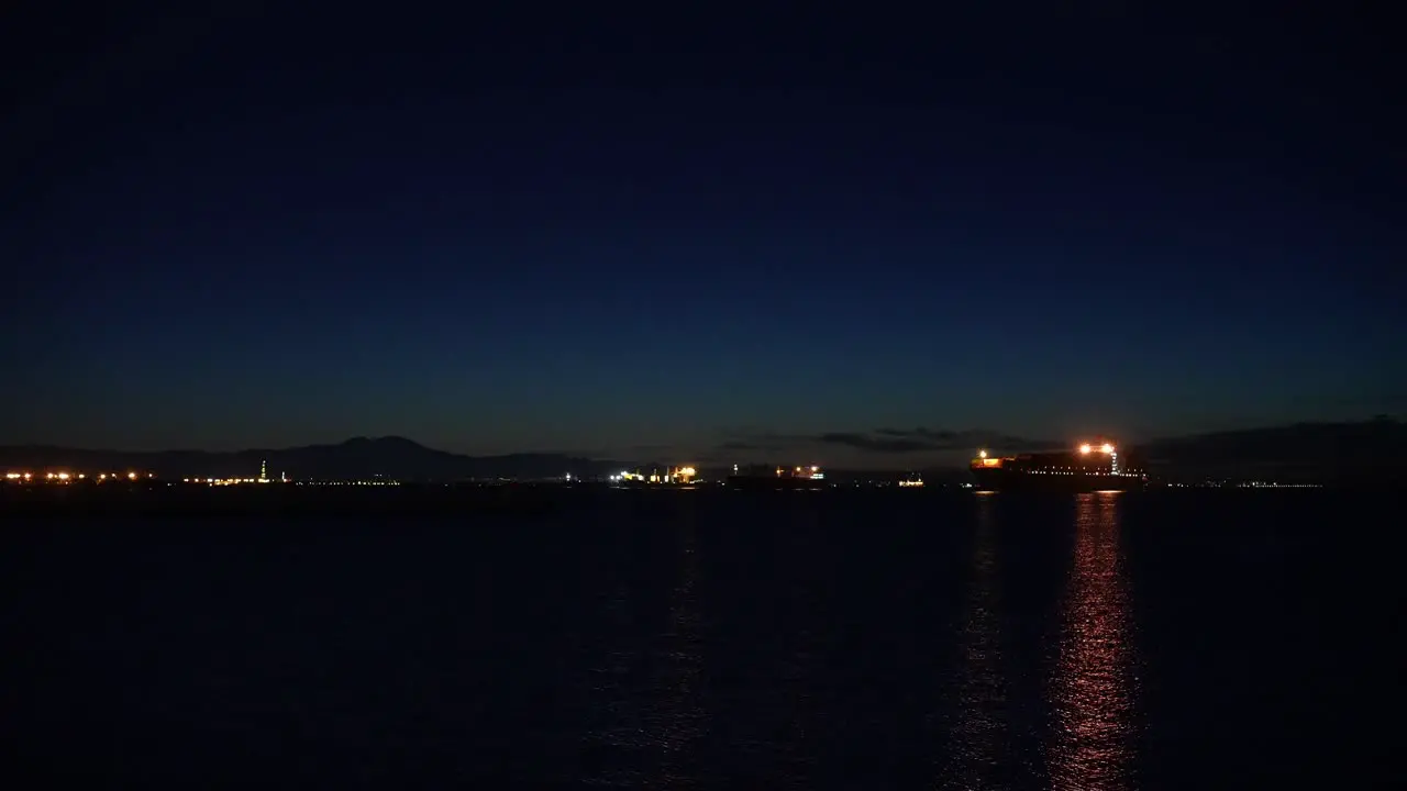 Transport shipping container cargo ships docked in the harbor at night waiting to be loaded or unloaded during a global supply chain crisis