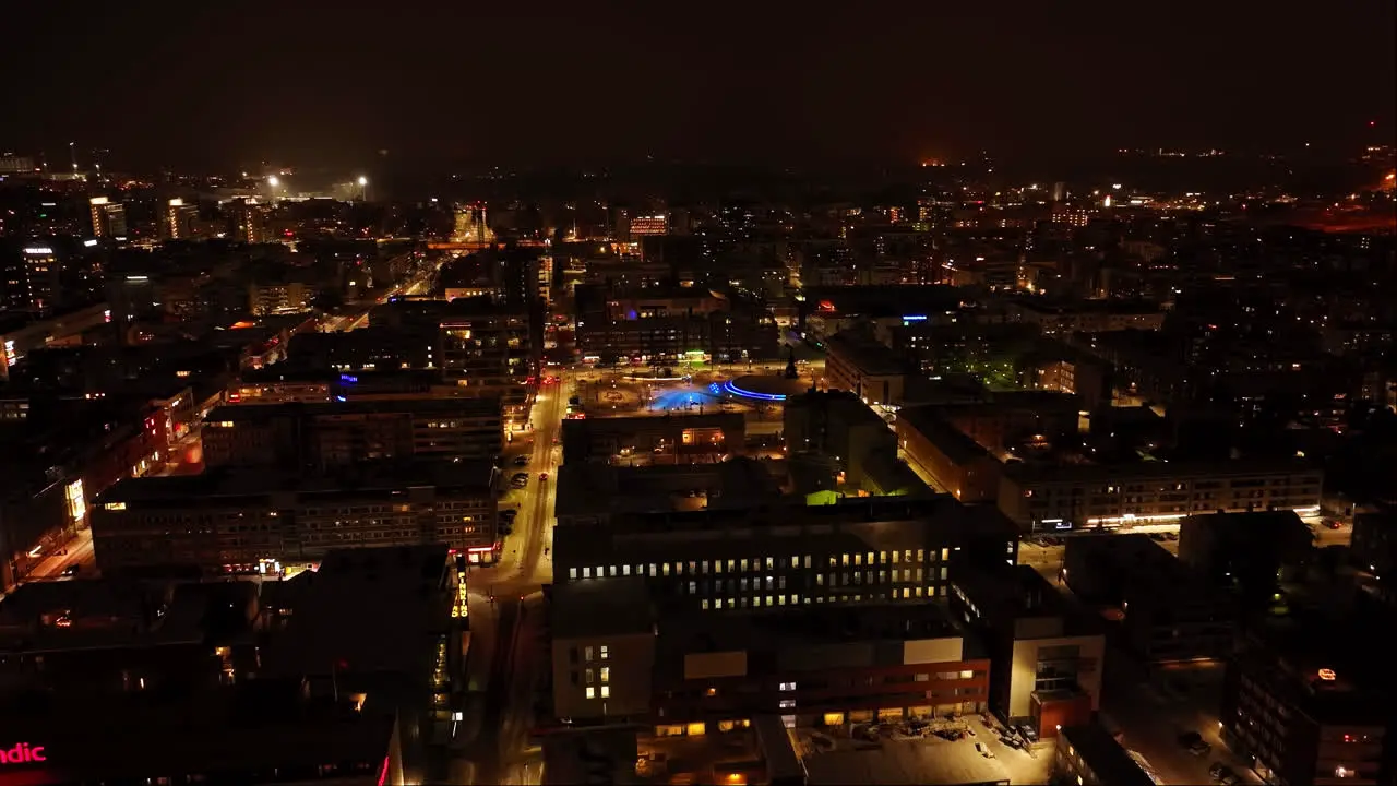 Cinematic drone overview of illuminated streets of Oulu winter night in Finland