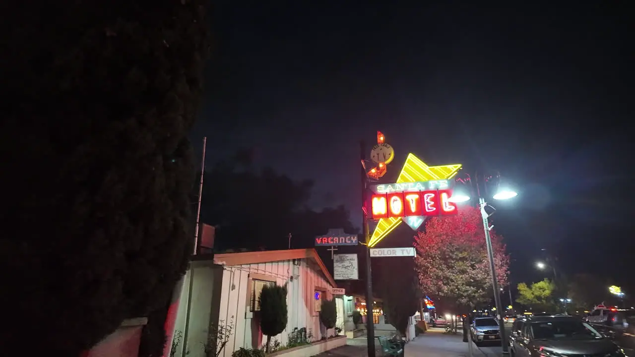 Walking along the sidewalk to reveal the Sant Fe Motel at nighttime