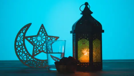 Tracking Shot of a Lantern Water and Dates On Table During Dusk Ramadan Celebrations