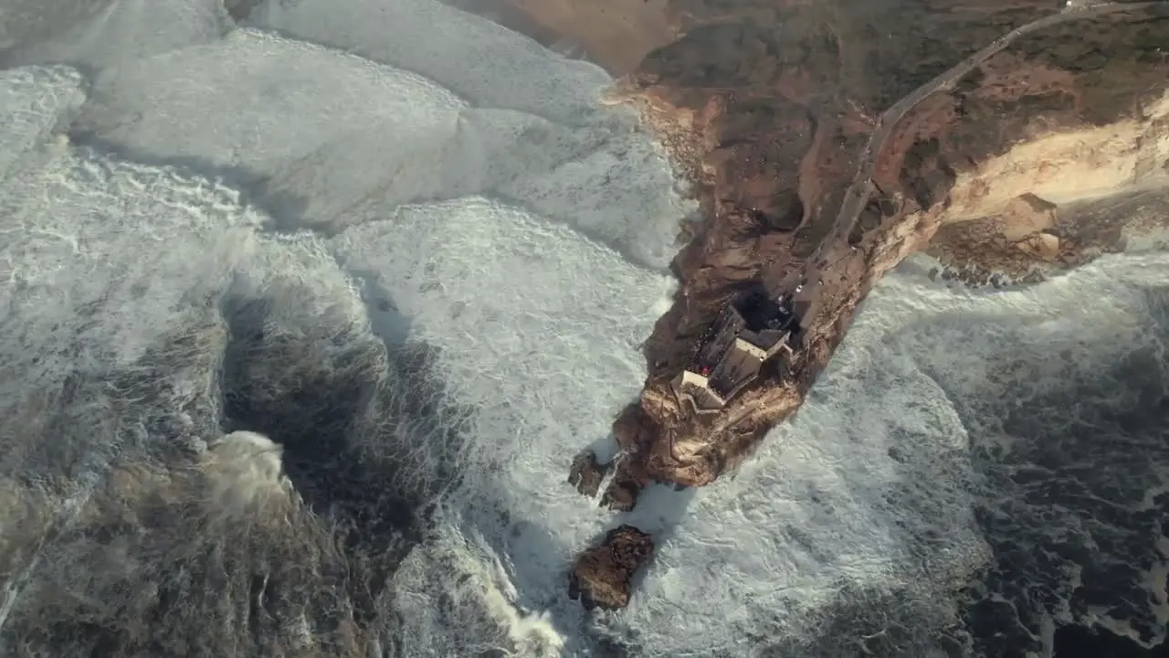 Nazare cliff and huge foamy waves spinning aerial shot