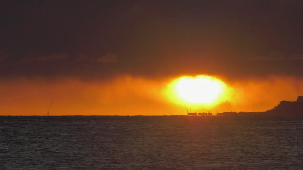 Sun on ocean horizon with dark clouds