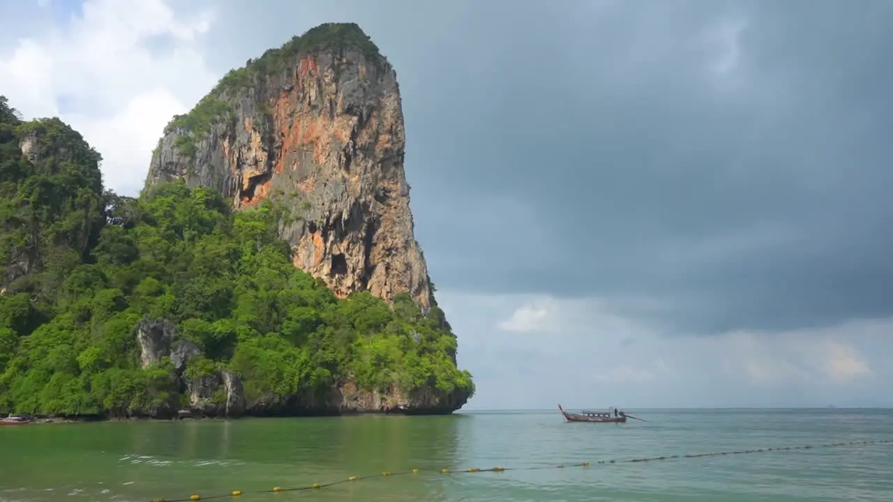 Railay beach Thailand Limestone Cliffs With Longtail boat and storm clouds