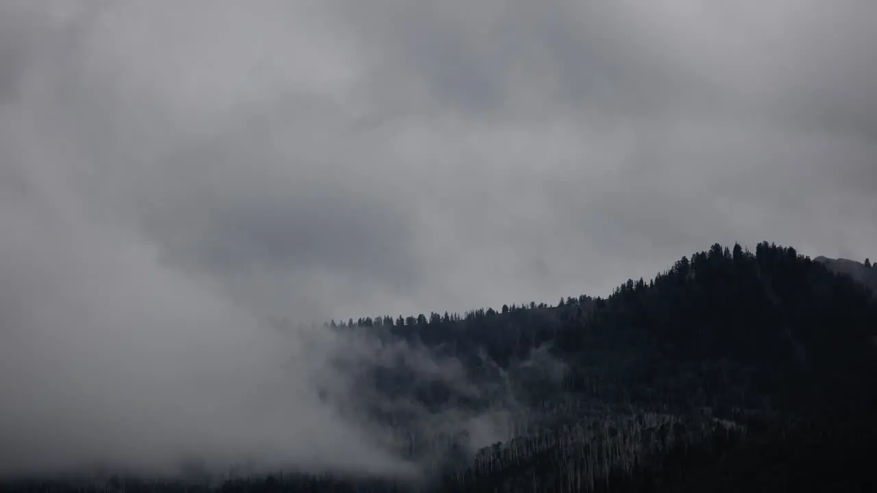 Timelapse of fog rolling out from mountain as storm clouds move in