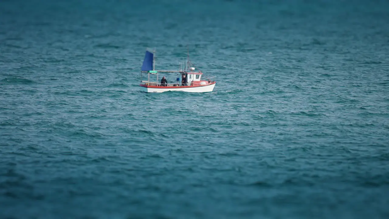 A lone fishing boat with one fisherman aboard riding the waves in the rough northern sea