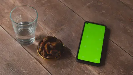 High Angle Shot of Water and Dates On Wooden Table with Green Screen Phone