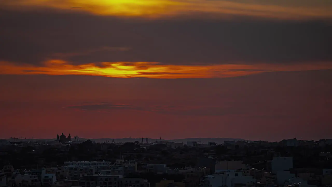 The sun breaks through the clouds in an orange glow at sunset in Malta