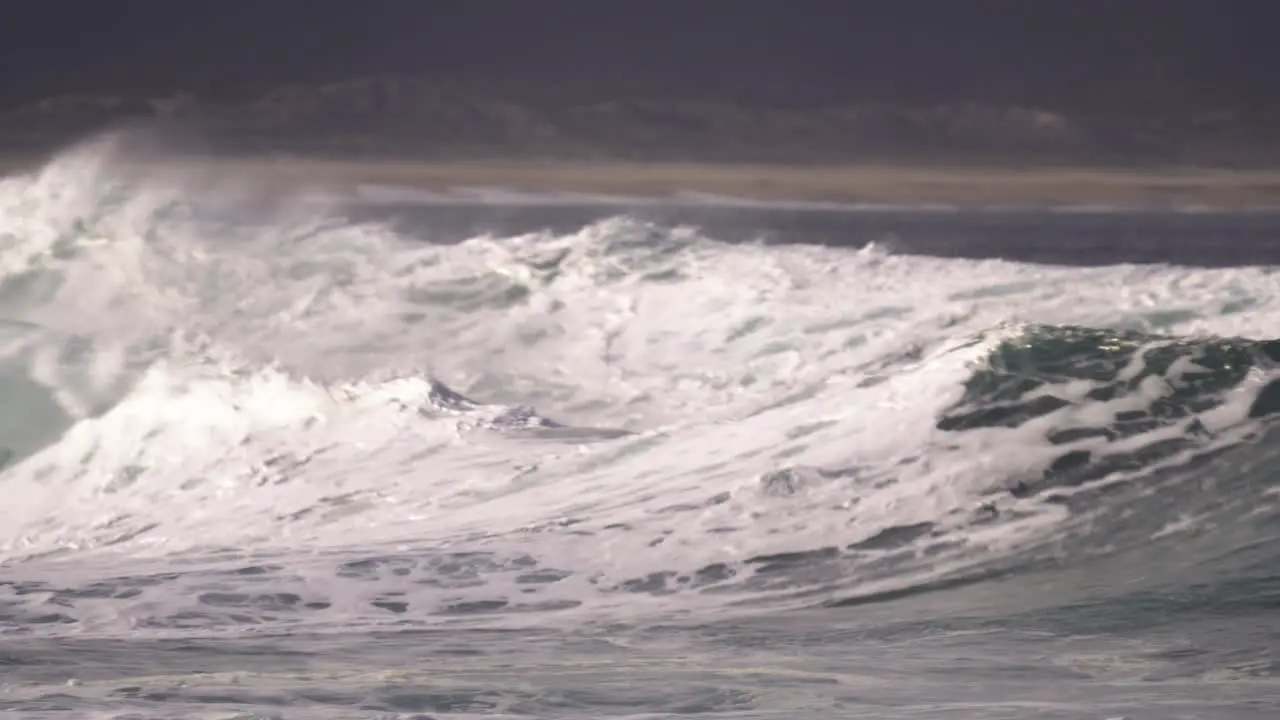 Surfer finishes the ride by jumping over the wave where jetski driver is waiting to take him to safety