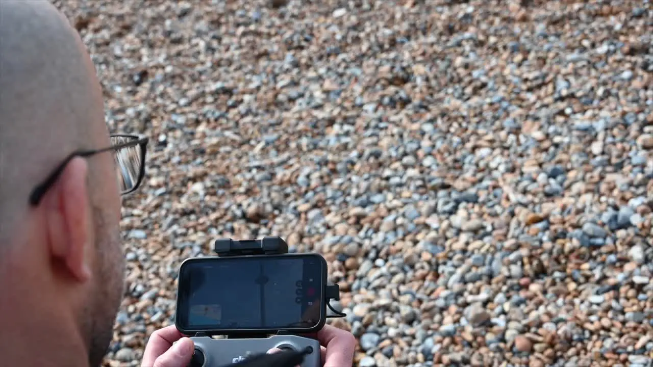 a man who wears glass is on a beach Brighton united kingdom and he is piloting a drone