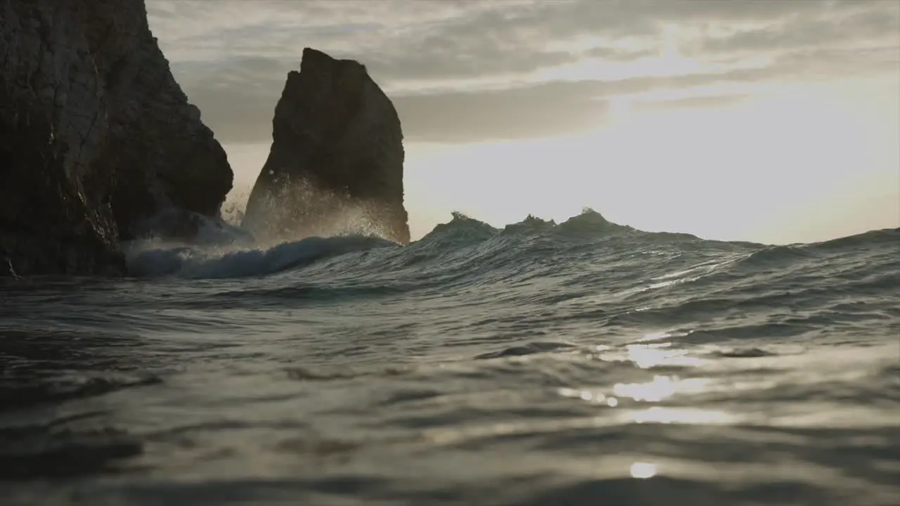 Waves crashing into rocks in golden hour