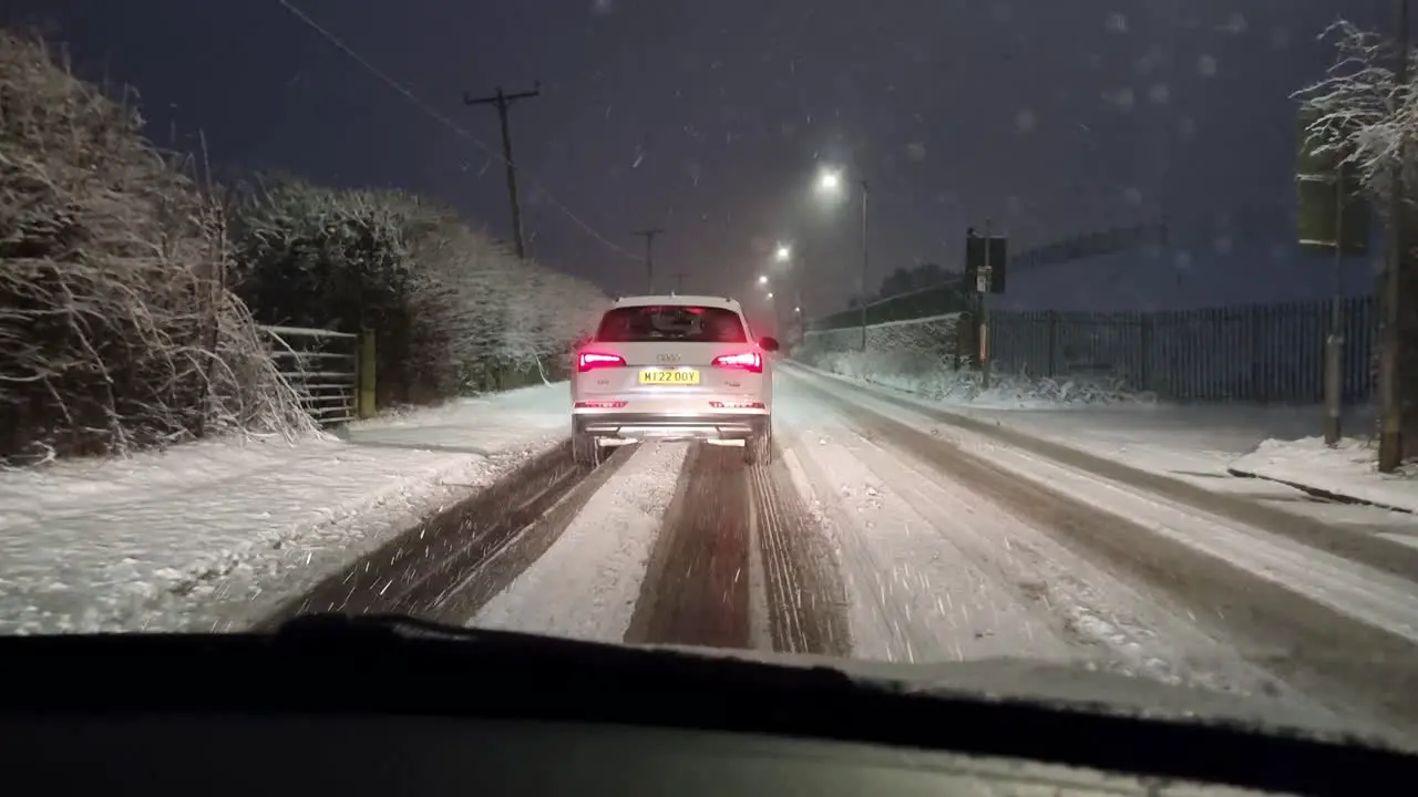 Windshield POV carefully driving in snowy slow traffic at night