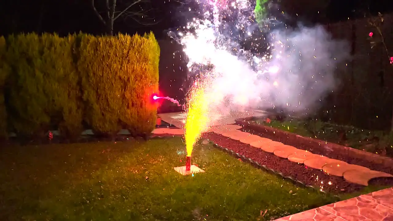 Ground-based Firecrackers starts to shoot out smoke and fire on the backyard during nighttime