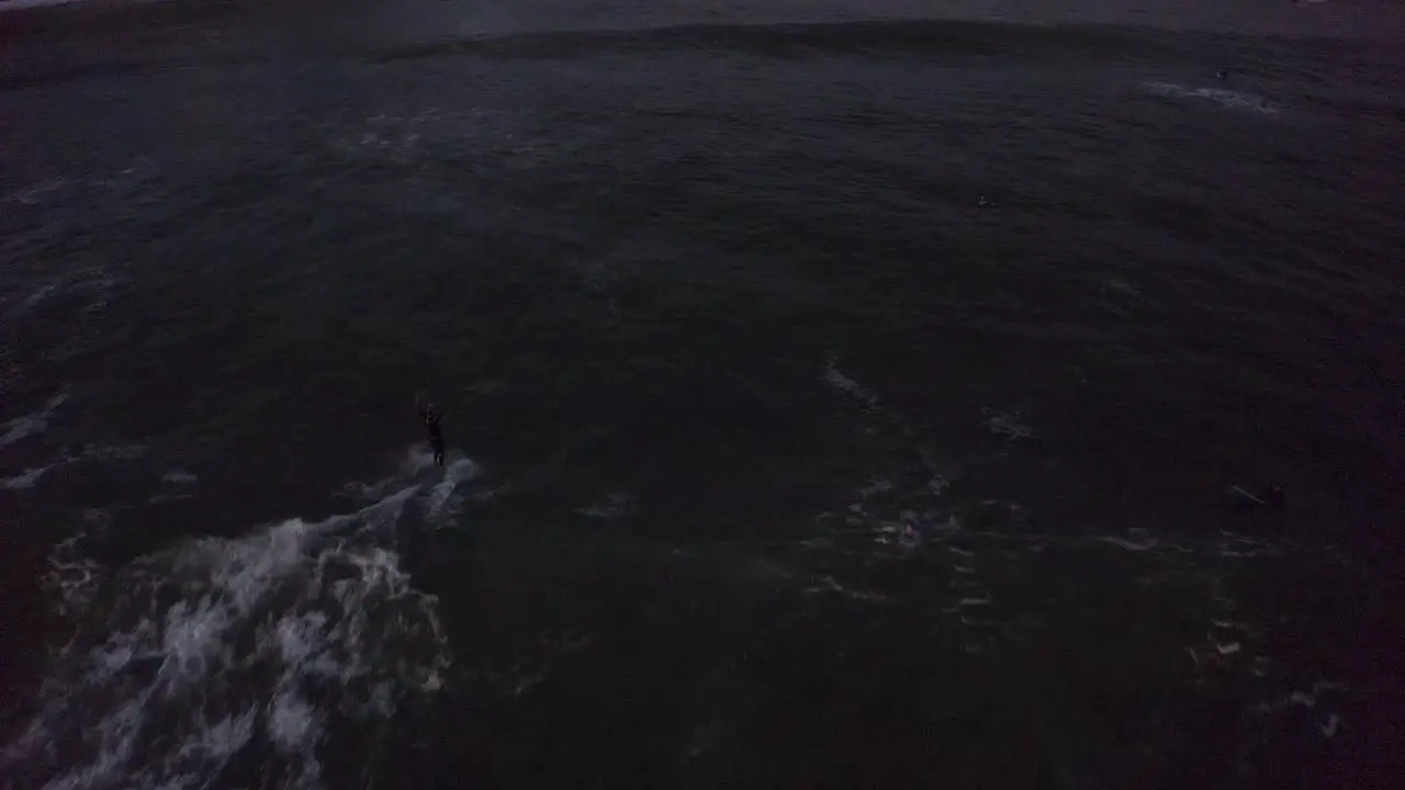 aerial tracking shot of the waves crashing during a night surf at cascais beach