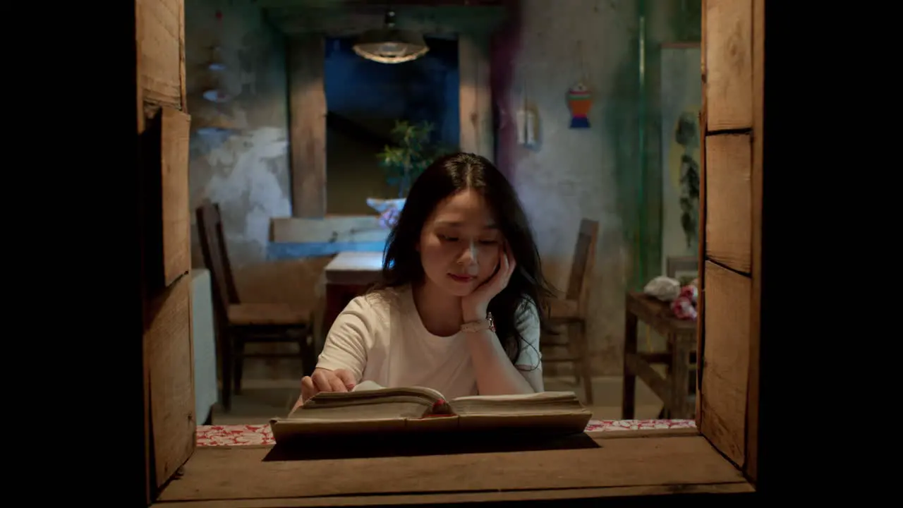 young woman casually reads a book while enjoying the night air