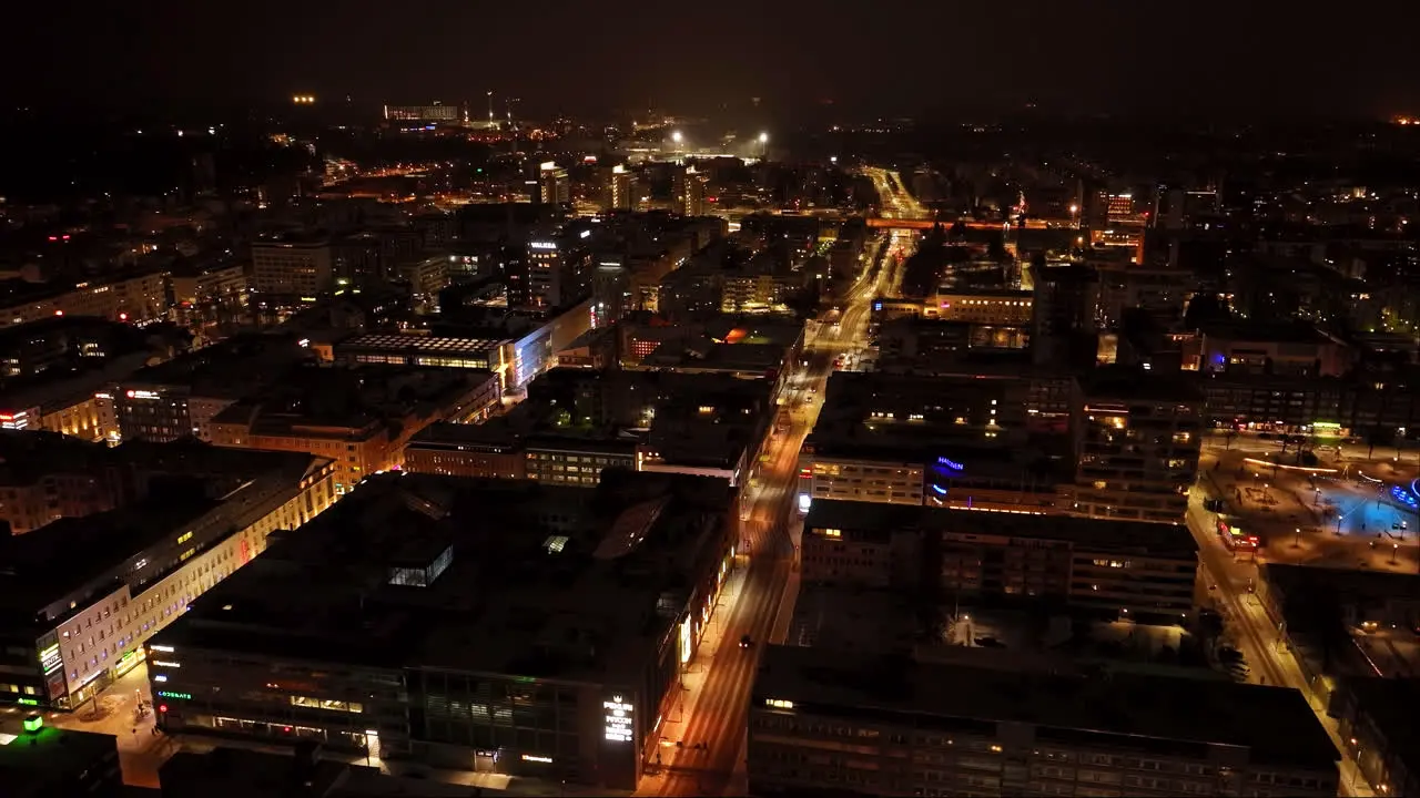 Aerial tracking shot overlooking night lit streets of Oulu city winter in Finland