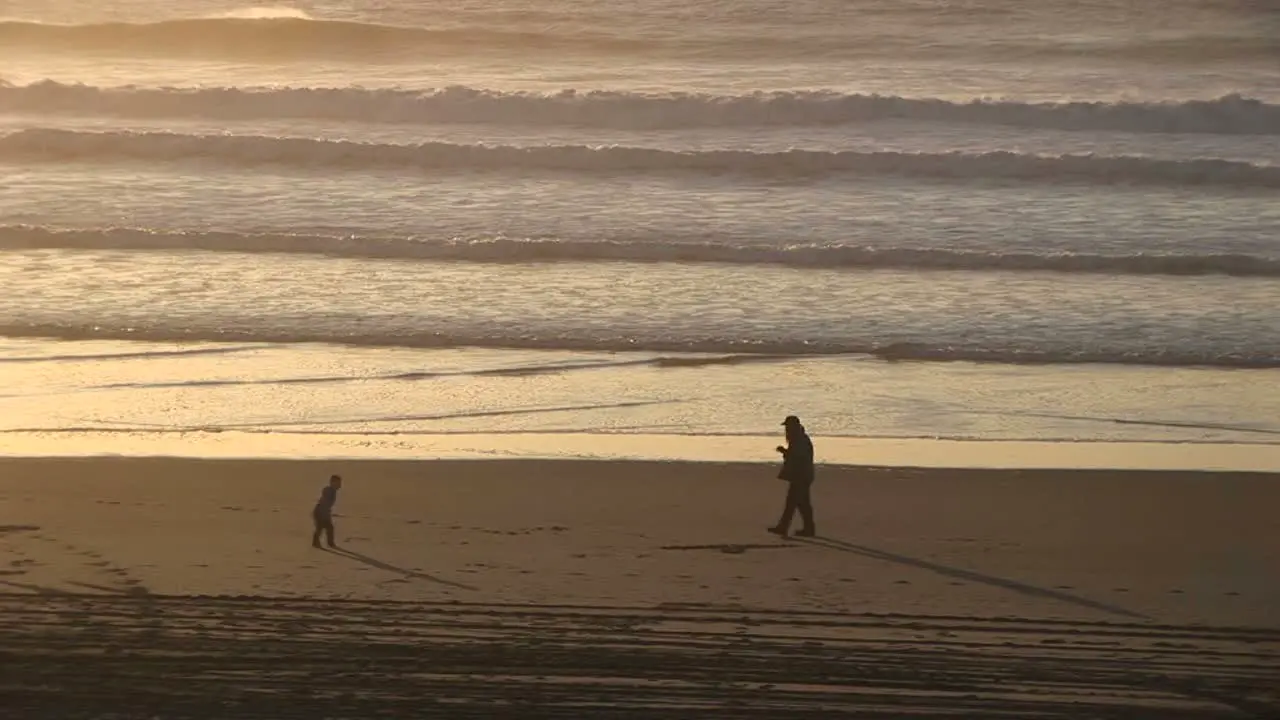 A Man Smokes A Cigarette On A Deserted Beach While A Young Boy And Girl Play Around Him