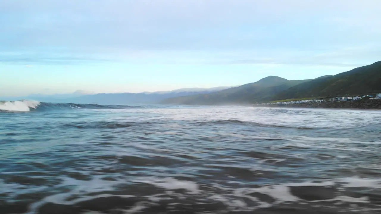 Aerial drone flying fast and low over the water surface of the Pacific ocean waves in Ventura California at sunrise