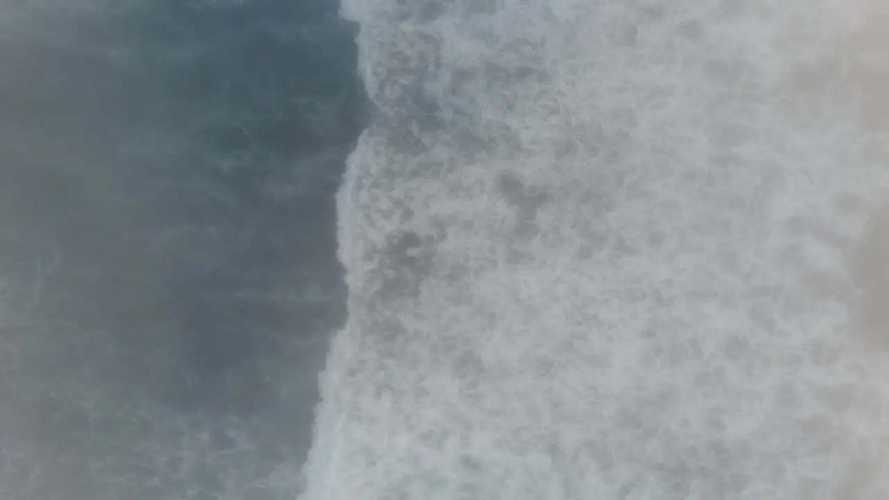 A top-down drone shot of waves rolling by in the fog on the Oregon Coast