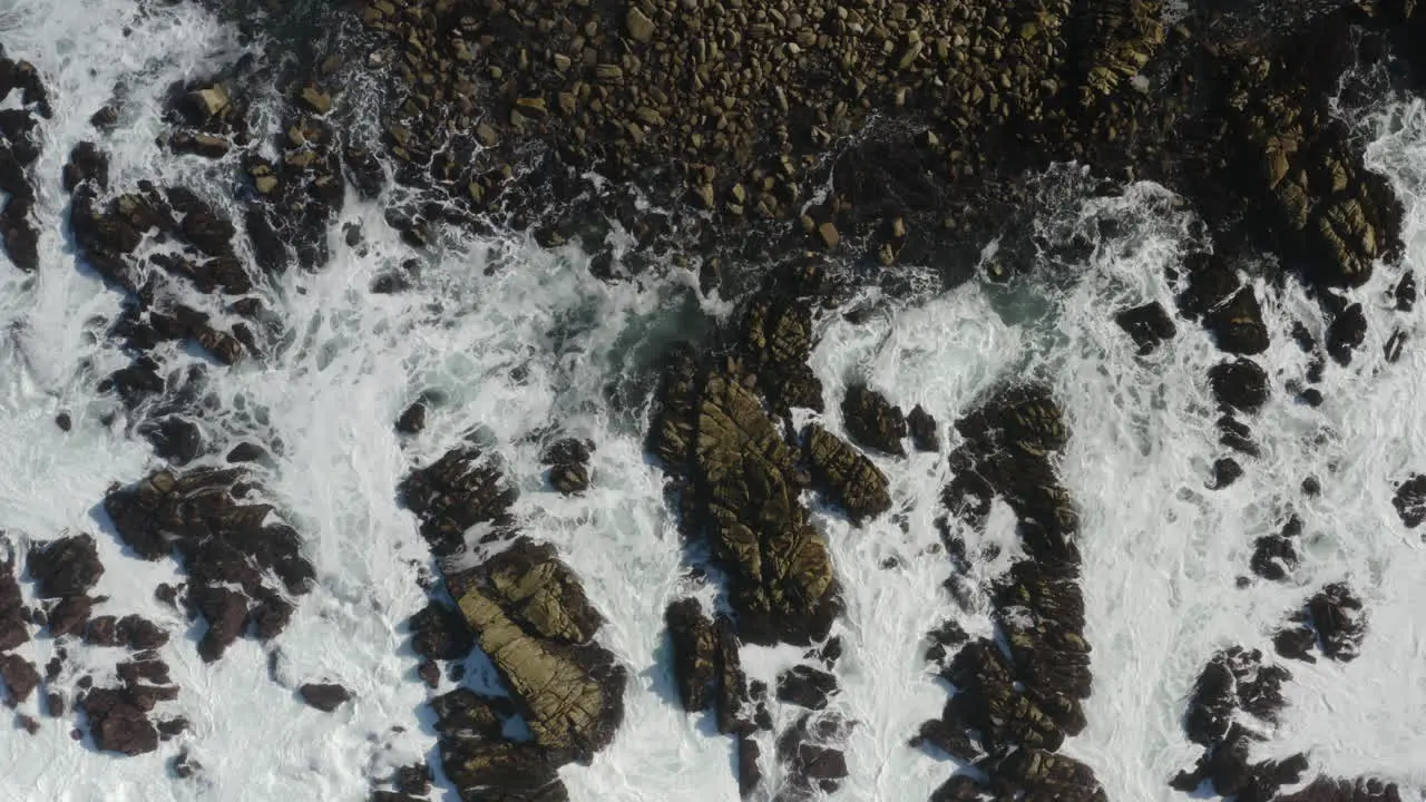 4K cinematic overhead pullback of giant waves breaking on coastal rocks