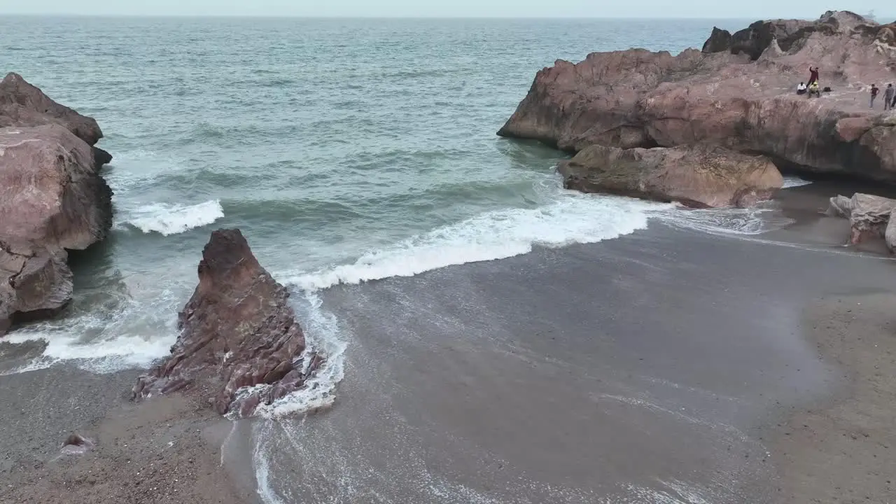 Aerial drone rotating shot over beautiful waves crashing on rocky beaches of Gadani Pakistan during evening time