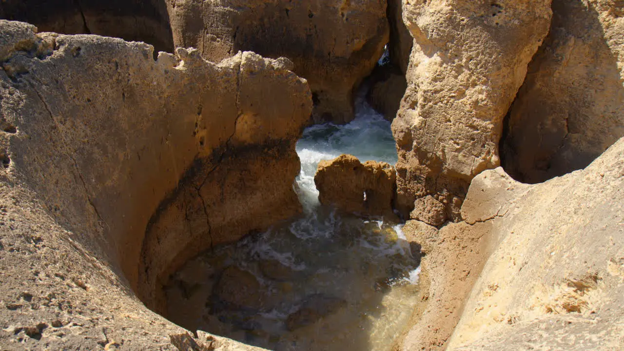 Waves Crashing Between Gaps On The Limestone Cliffs Of Algarve Portugal