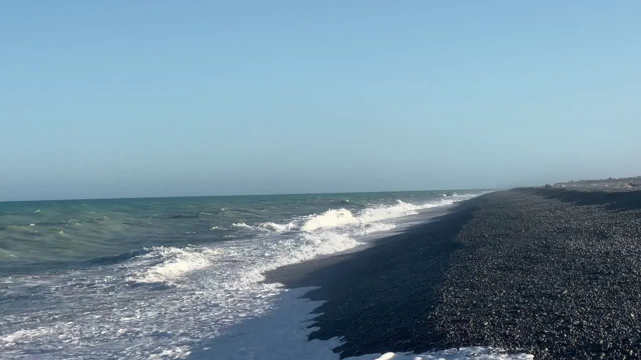 Strong large waves crashing ashore a long rocky beach at sunset