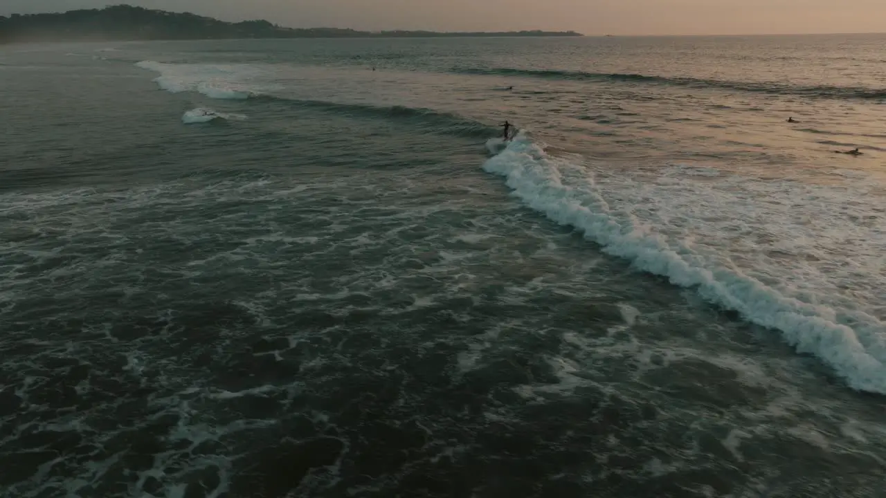 Surfers Riding Big Waves At Guanacaste Beach In Costa Rica At Sunset aerial drone shot