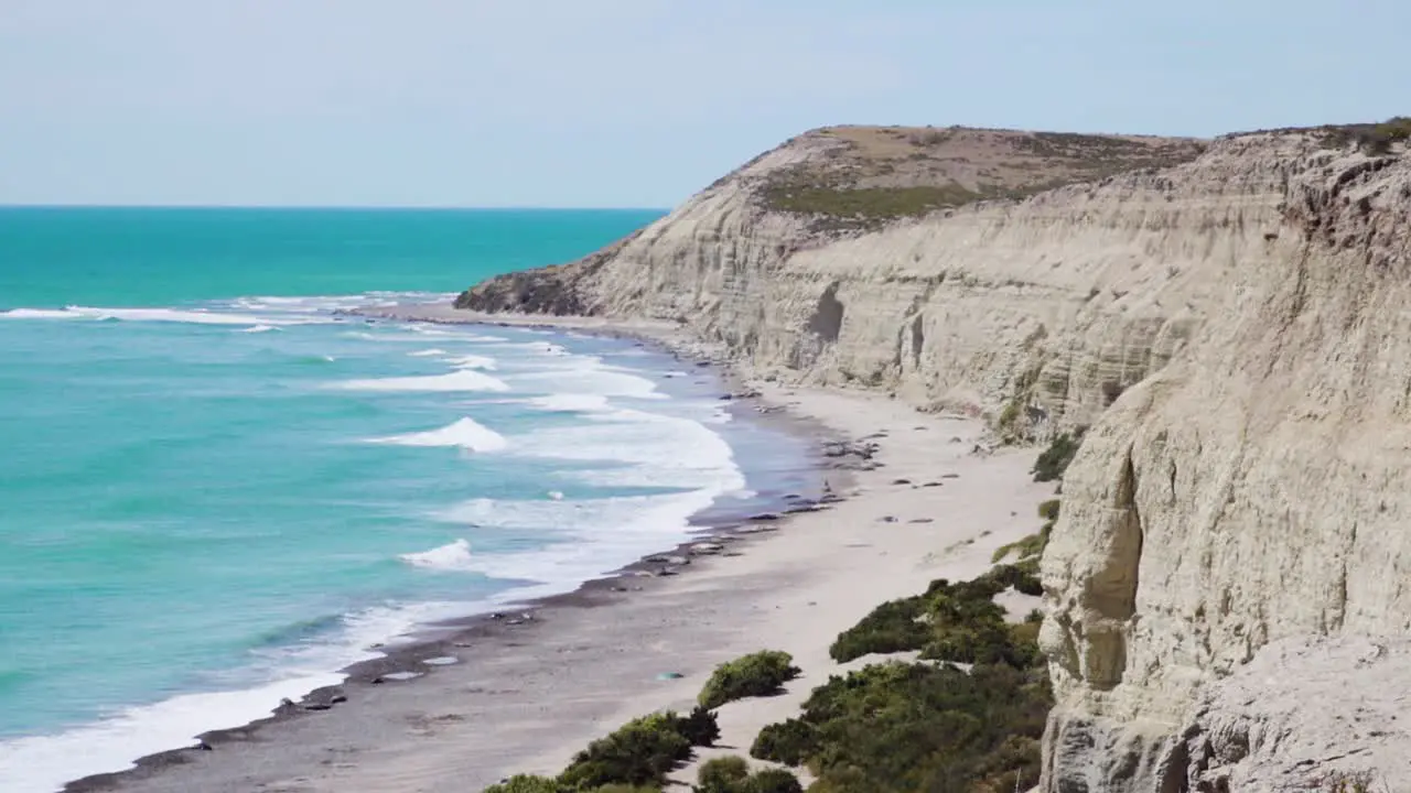 Scenery Of Crashing Waves And Sandy Cliff's With Seals Near Shoreline In Patagonia Argentina