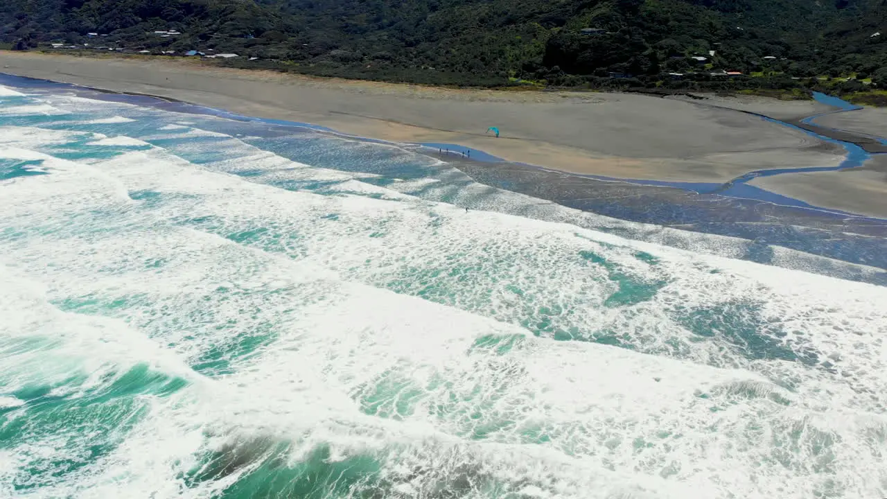 White Surfing Waves With Man Windsurfing At Piha Beach In New Zealand