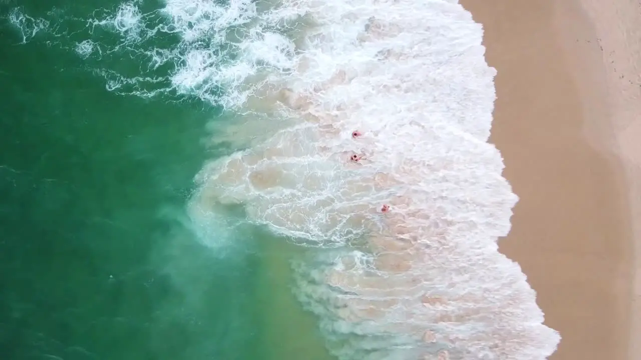 Drone aerial top view of three people having a swim in the beach in Sydney Australia