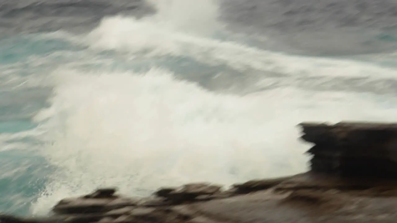 Rough ocean waves churn and crash against rocks panning medium shot