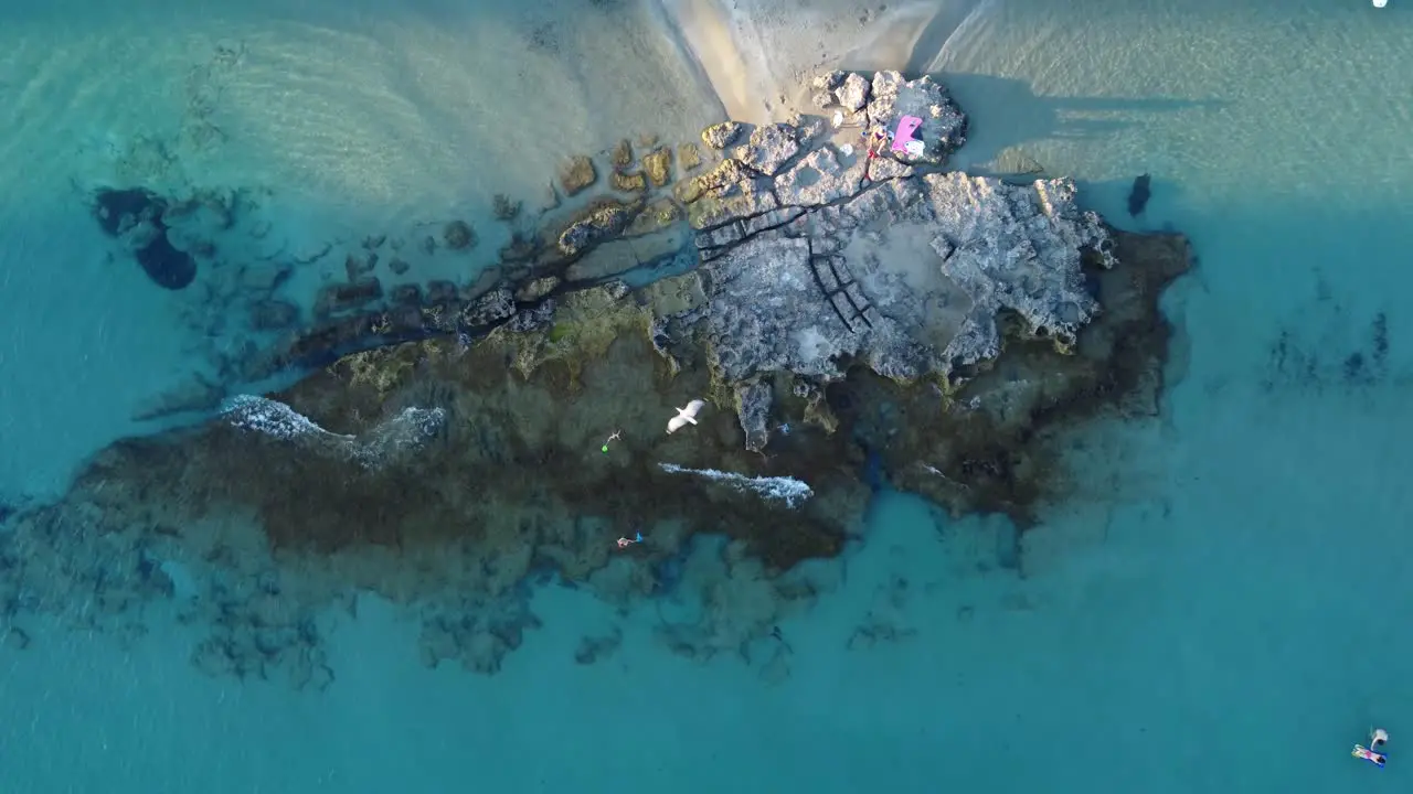 Drone clip moving upwards over a rock formation on the edge of a tropical beach in Calpe Spain