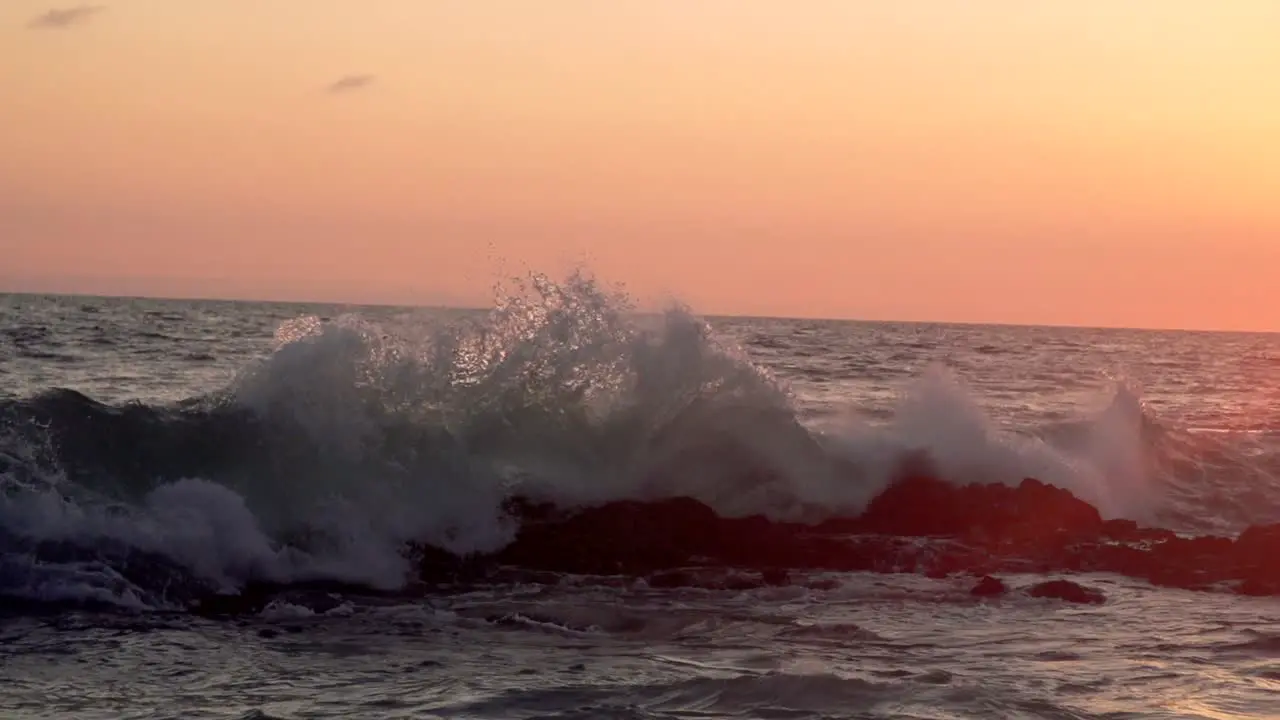 Super slow motion wave crashing on a reef in front of sunset in California