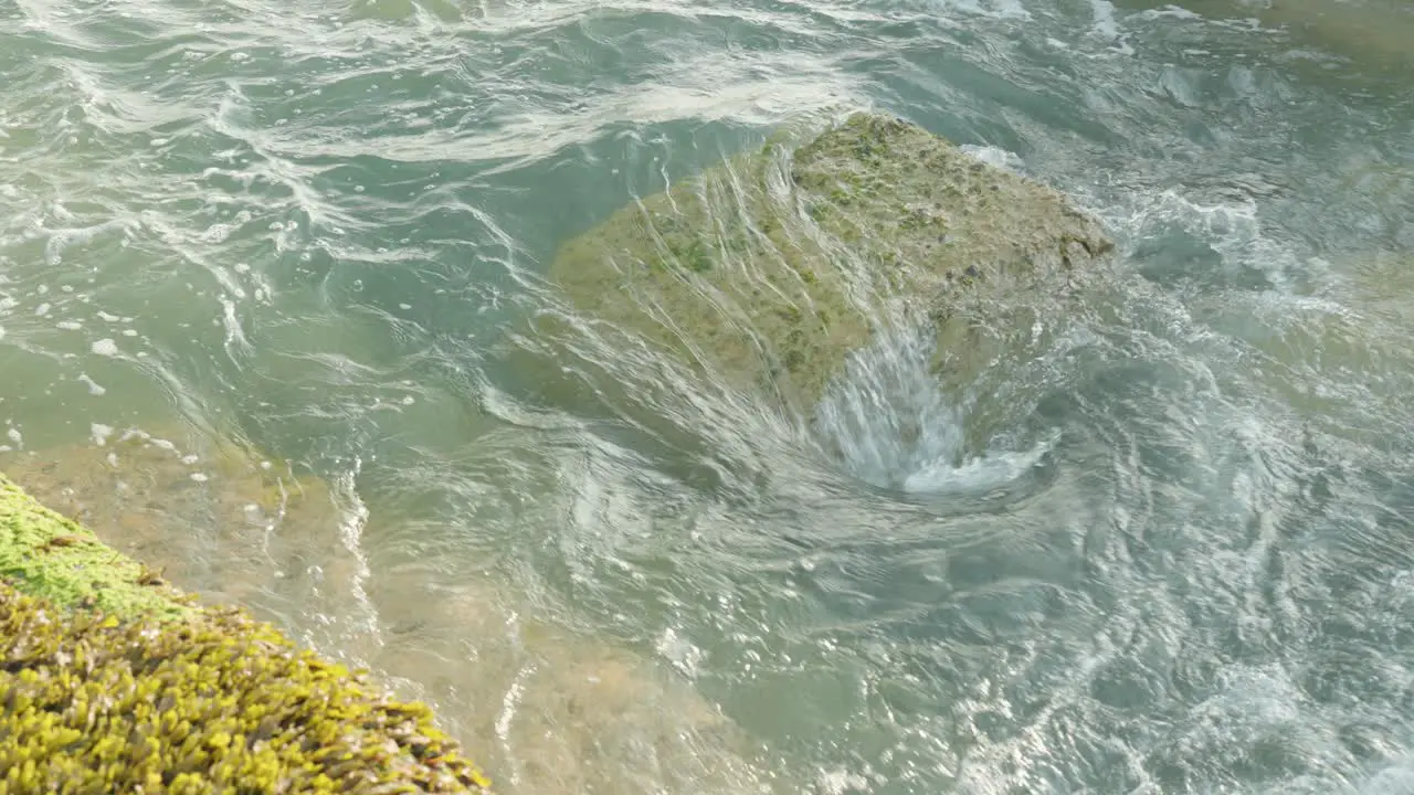 Slow motion close up of waves hitting and passing a big coastal rock at the British sea in Seaford