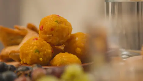 Close Up Of Laddoo And Samosas On Muslim Family Table In Home Set For Meal Celebrating Eid