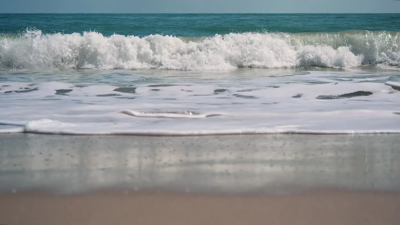 Slow motion low angle shot showing breaking waves on sea shore during beautiful day