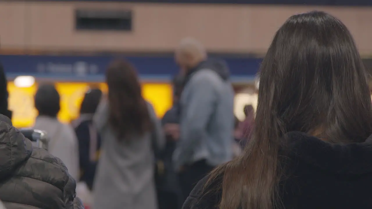 Woman sitting in train station with people passing by