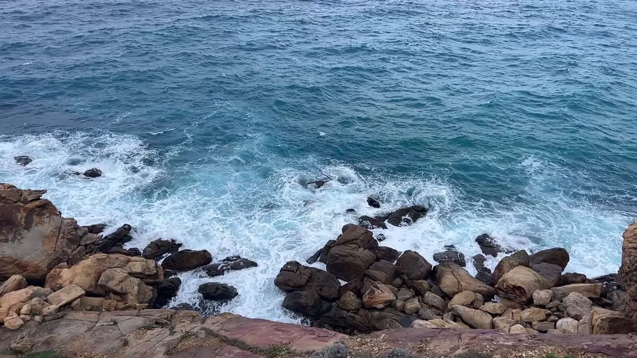 Slow motion view of waves breaking at rocky shoreline