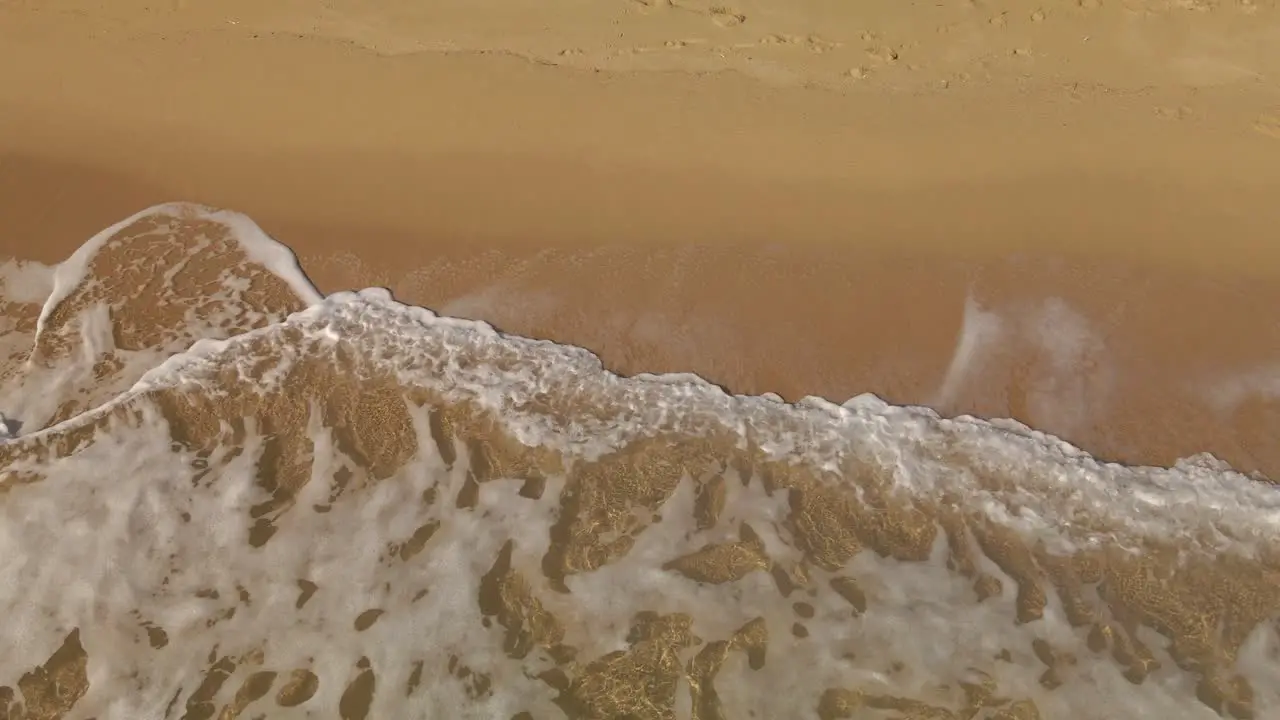 Ocean waves white sea foam rolling into a golden sand empty beach in Costa Brava Spain