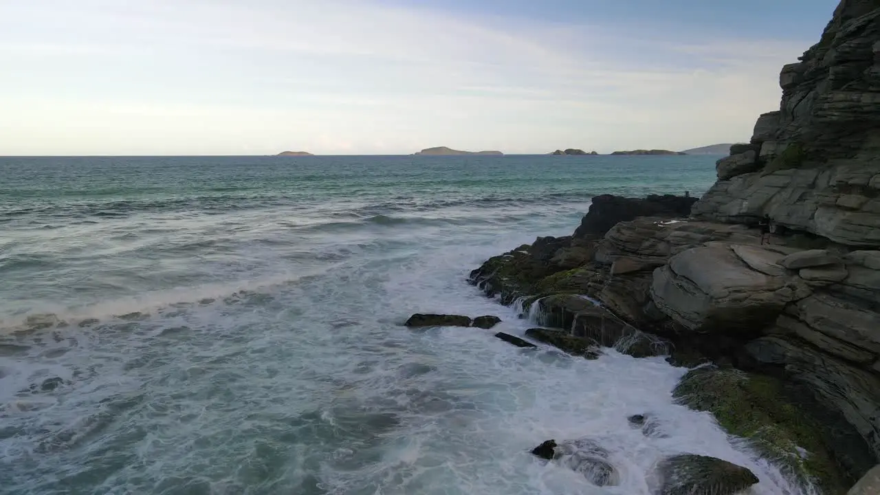 Ocean waves splashing into rocky cliff side in Geriba Beach en Buzios Brasil