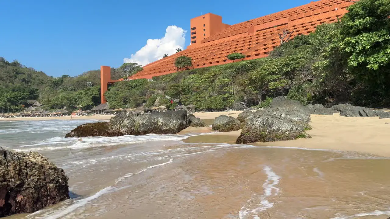 Surf washing on sunny sandy beach in front of tropical resort