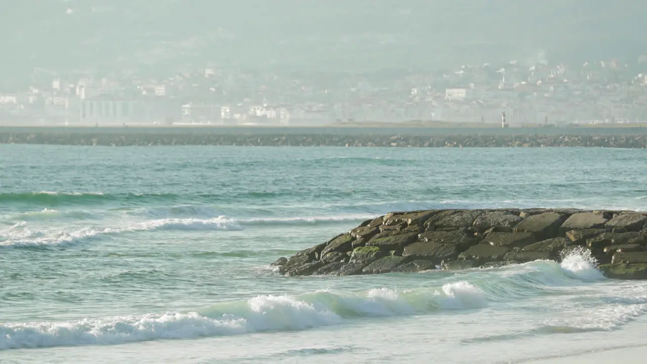 Tidal Waves Against Breakwater With Misty City Landscape At Figueira da Foz Portugal