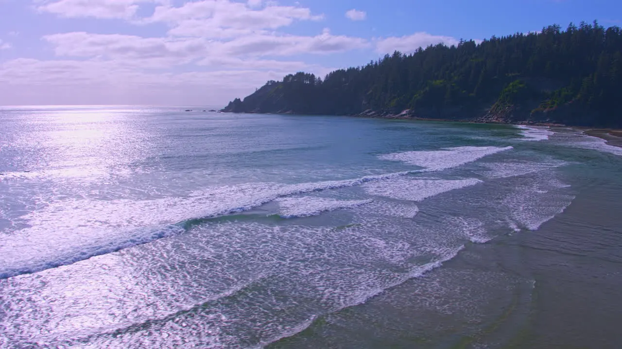 Aerial flying forward near shore over sand ocean waves