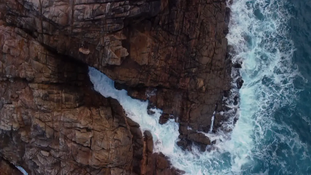 Top Down View Of Foamy Waves Splashing On Rugged Cliffs In Arteixo Spain drone shot