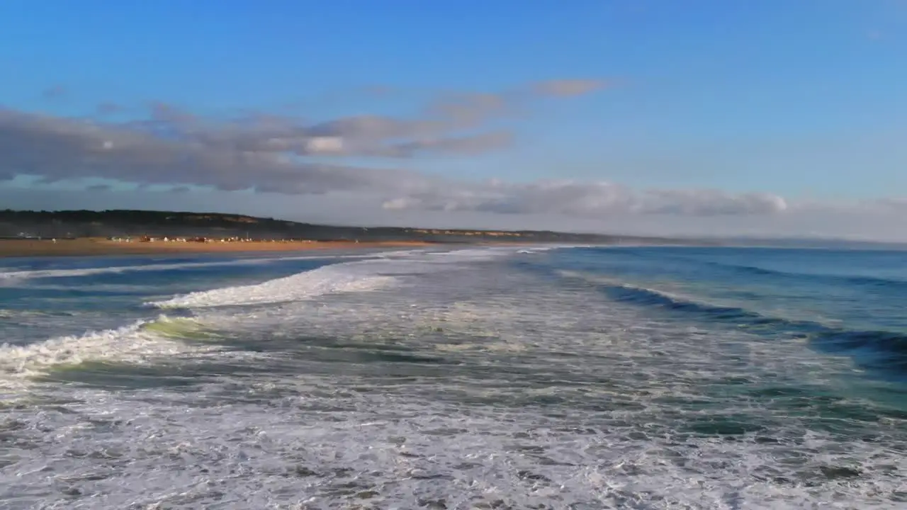 Drone footage of the foamy water of waves rolling in by Costa Da Caparica in Portugal