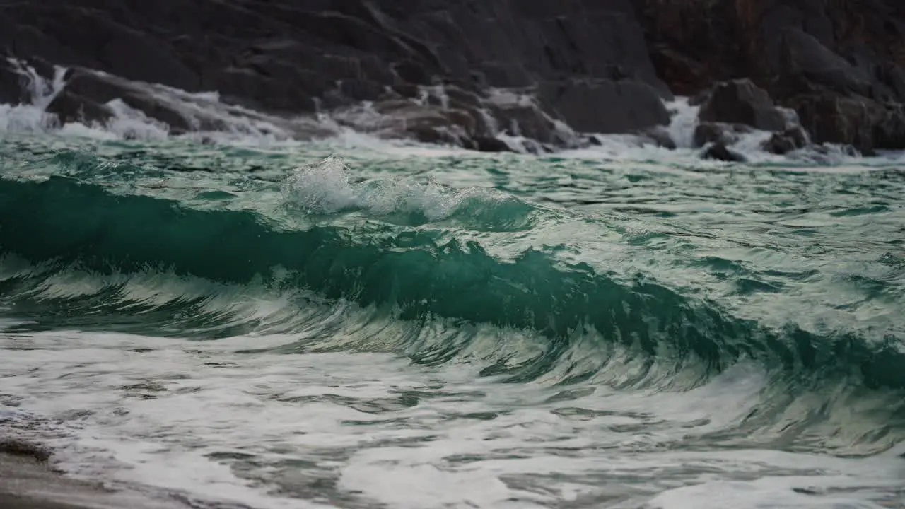 Powerful waves are crashing on the rocks and spilling on the sandy shore