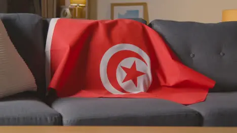 Flag Of Tunisia Draped Over Sofa At Home Ready For Match On TV